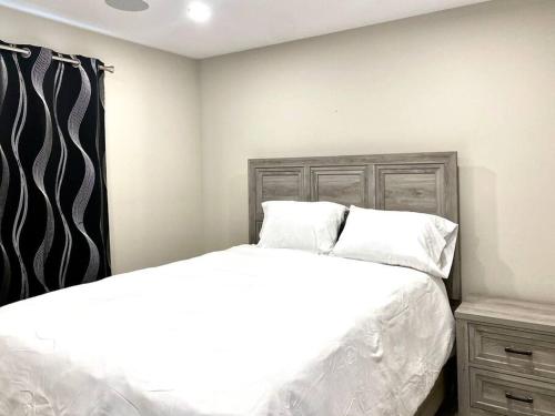 a bedroom with a bed with white sheets and pillows at Modern & Luxurious Private Suite in Regina in Regina