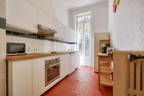 Il comprend une cuisine avec des placards blancs et du carrelage rouge. dans l'établissement NOCNOC - Le Liberté, à Marseille