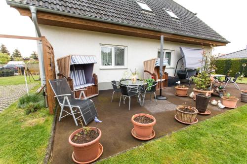 un patio con mesa, sillas y macetas en Ferienwohnung Gustel, en Freest
