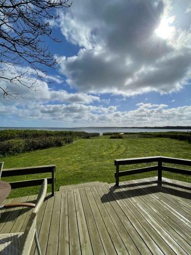 ボルコップにあるSummer House At Hvidbjerg Beach With Sea Viewの木製デッキに座って水辺を眺めるベンチ2台