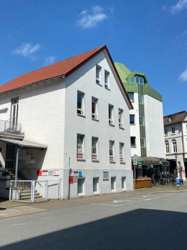 ein weißes Gebäude mit rotem Dach auf einer Straße in der Unterkunft CITYNA Apartment Bielefeld - Late Check-Out in Bielefeld