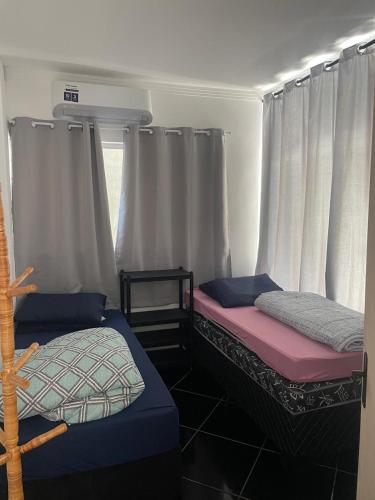 2 camas en una habitación con cortinas blancas en Pousada Aeroporto Viracopos Campinas, en Viracopos