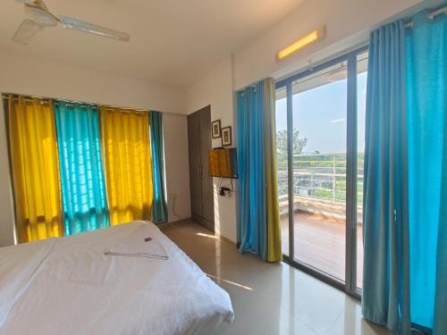 1 dormitorio con cortinas coloridas, 1 cama y balcón en Quality Hospitality Services, en Pune