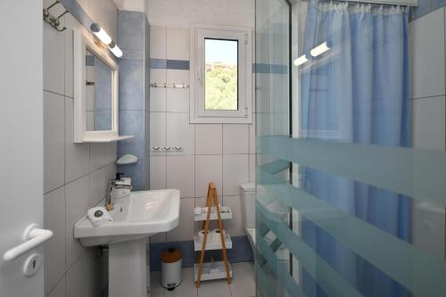 uma casa de banho azul e branca com um lavatório e uma janela em Paradise Apartments em Ferma