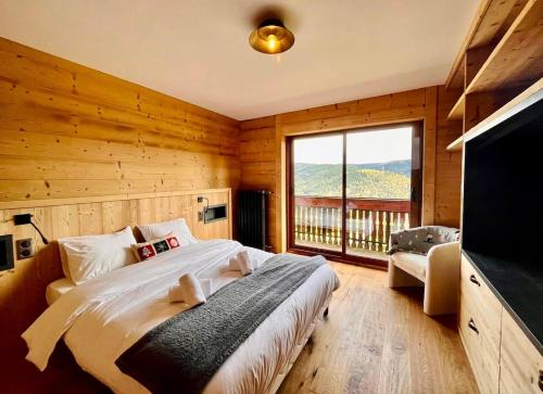 - une chambre avec un grand lit et une grande fenêtre dans l'établissement Le Vénérable, 4 étoiles, vue imprenable au coeur des Vosges, à Ventron