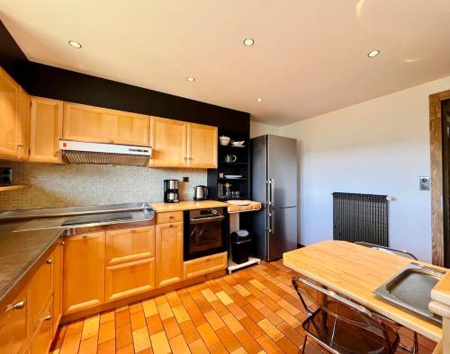 une cuisine avec des placards en bois et une table en bois dans l'établissement Le Vénérable, 4 étoiles, vue imprenable au coeur des Vosges, à Ventron