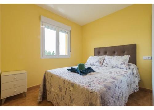 Un dormitorio con una cama con paredes amarillas y una ventana en El Trabaz, en Candamin