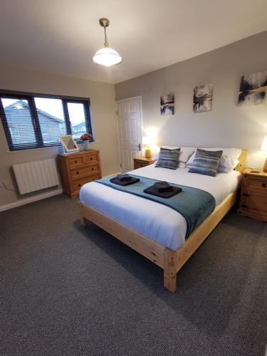 a bedroom with a large bed and two windows at River Bay - Norfolk Broads in Brundall