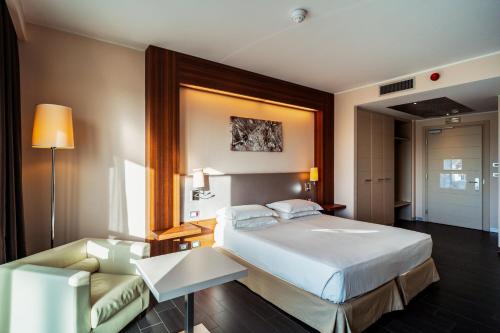 オルビアにあるダブルツリー バイ ヒルトン オルビア サルデーニャのベッドとソファ付きのホテルルーム