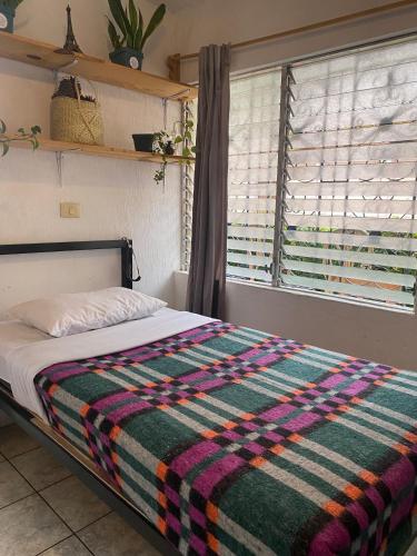 een slaapkamer met een bed met een kleurrijke deken erop bij Nomades Hostel "The Apartment" in Panajachel