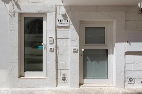 a white building with two windows and a door at WePuglia - Vista Cattedrale in Monopoli