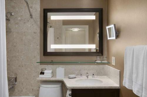 a bathroom with a sink and a mirror and a toilet at Fairmont Royal York Hotel in Toronto