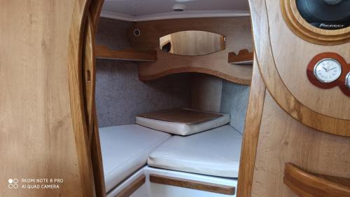 Habitación pequeña con 2 camas y reloj en Jacht motorowy Calipso 750, en Ryn