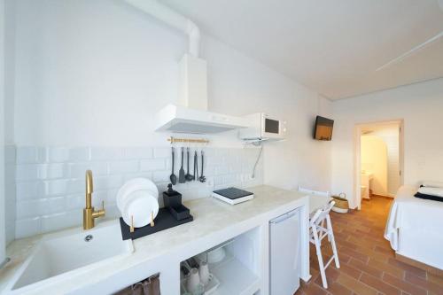 a white kitchen with a sink and a bed at Lirondo in San José