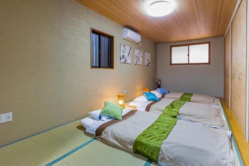 una camera da letto con un grande letto con cuscini verdi e bianchi di Fukujutei / Vacation STAY 6332 ad Osaka