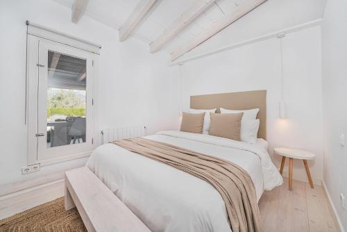 a white bedroom with a large bed and a window at Casa Blanca in El Port de la Selva