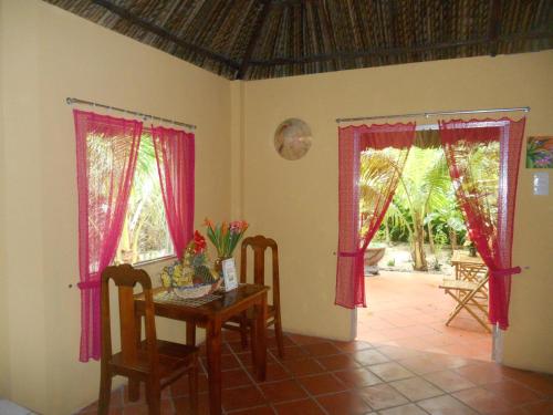 a dining room with red curtains and a table at Thuy - Gunter Garden Bungalow in Mui Ne