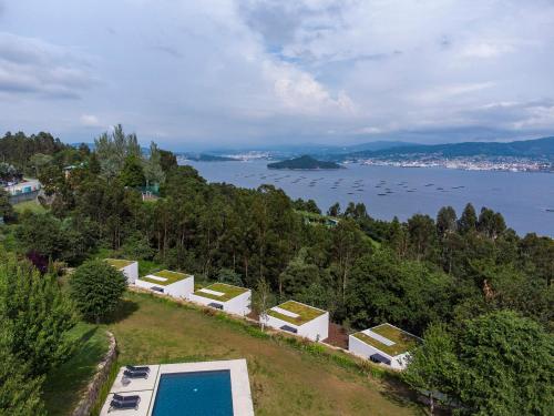 een huis met een zwembad op een heuvel naast het water bij Hotel Pepe Vieira Relais & Châteaux in Raxo