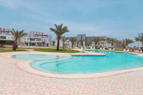 una piscina in un resort con palme e edifici di PARADISUS PARACAS Gran Casa de Playa con Jacuzzi! a Paracas