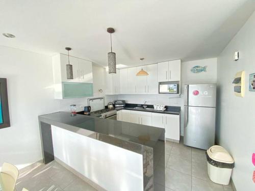 uma cozinha com armários brancos e um frigorífico de aço inoxidável em PARADISUS PARACAS Gran Casa de Playa con Jacuzzi! em Paracas