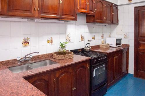 cocina con armarios de madera, fregadero y fogones en Aires de Salta II 3 pisos por escalera en Salta