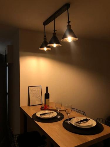 einen Tisch mit 2 Tellern, Weingläsern und Lampen in der Unterkunft Blue apartman in Žarkovo