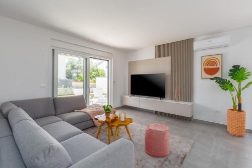 a living room with a gray couch and a tv at Holiday Home Blossom by SeeAdria in Karpinjan