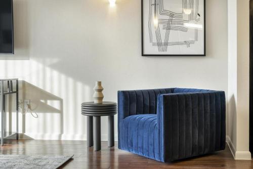 una silla azul en una sala de estar con mesa en Landing at Axis Waterfront - 1 Bedroom in Downtown Benbrook, en Fort Worth