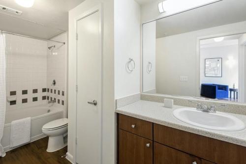 een badkamer met een wastafel, een toilet en een spiegel bij Landing at Axis Waterfront - 1 Bedroom in Downtown Benbrook in Fort Worth