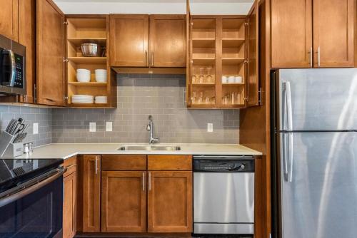 a kitchen with wooden cabinets and a stainless steel refrigerator at Landing at City North - 1 Bedroom in Valley Ranch in Irving