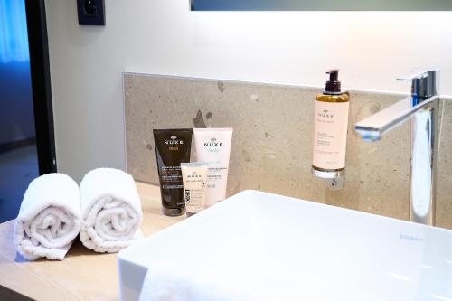 a bathroom counter with towels and a bottle of soap at Les Tanneurs in Namur