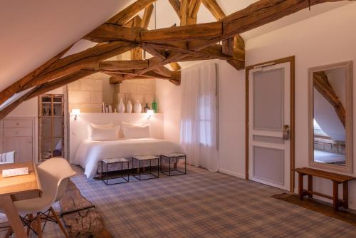 a bedroom with a white bed and a table and chairs at Le Domaine de Mestré, The Originals Relais in Fontevraud-l'Abbaye