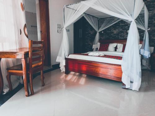 a bedroom with a canopy bed and a desk at Queen's Way Resort in Kisumu