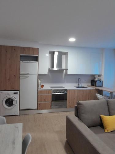 a kitchen with white appliances and a couch in a room at Apartamentos Mar y Playa in Moaña