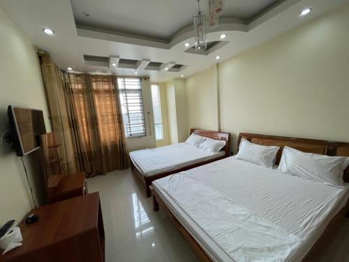 a bedroom with two beds and a desk at Bảo An Hotel- Tuần Châu Hạ Long in Ha Long