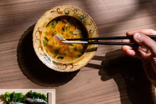 a person holding a bowl of soup with chopsticks at Cheval Blanc Paris & Dior Spa Cheval Blanc Paris in Paris