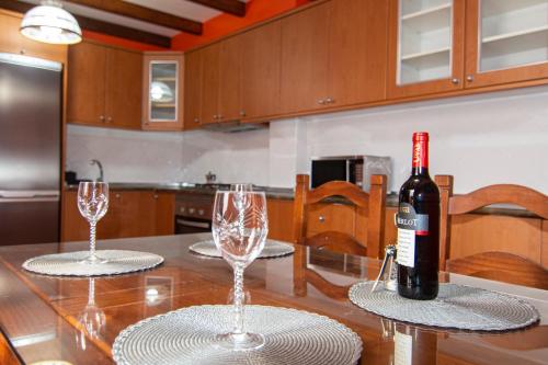 a bottle of wine sitting on a table with two glasses at Villa Florymar in Ingenio