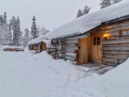 a log cabin covered in snow with a pile of snow at Holiday Home Keidaskero b 9 by Interhome in Pyhätunturi