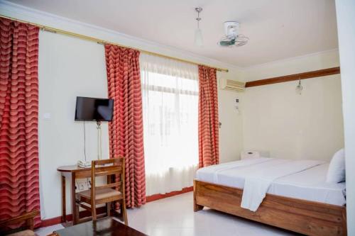 um quarto com uma cama e uma grande janela em Kilimanjaro Crane Hotel em Moshi
