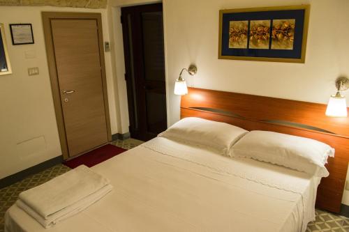 a bedroom with a white bed with a wooden headboard at B&B a Casa della Nonna Uccia in Nardò