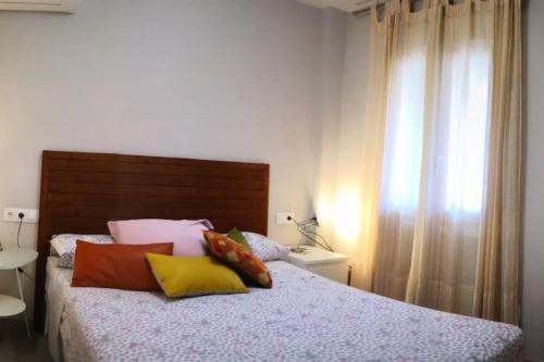 Un dormitorio con una cama con almohadas de colores. en Alojamientos Nerja Costa, en Nerja