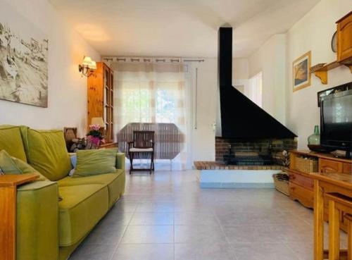 ein Wohnzimmer mit einer grünen Couch und einem Kamin in der Unterkunft Casa pareada con piscina in L'Escala