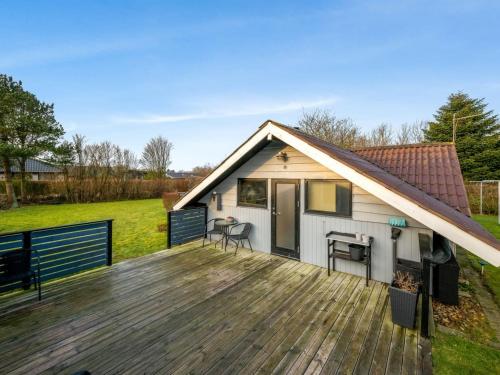 uma pequena casa com um deque de madeira num campo em Holiday Home Tjana - all inclusive - 6km from the sea by Interhome em Esbjerg
