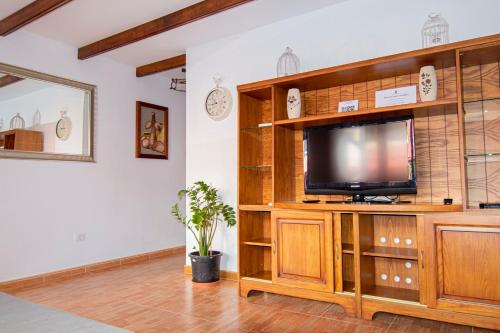 sala de estar con TV en un centro de entretenimiento de madera en Villa Florymar en Ingenio