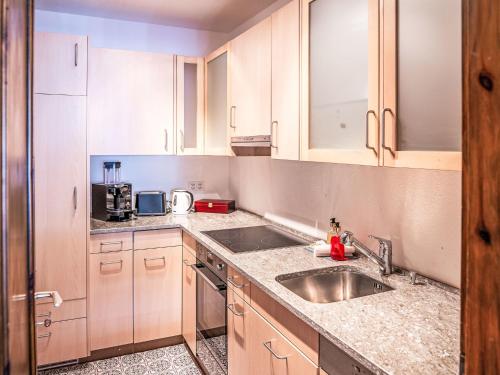 a kitchen with wooden cabinets and a sink at Apartment Chesa Murtel by Interhome in Surlej