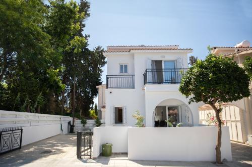 a white house with a fence and a tree at Taheli Riverside Townhouse in Tourist Area in Paphos