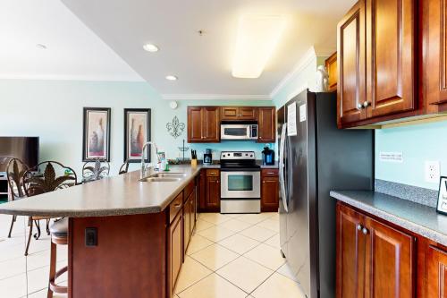 a kitchen with wooden cabinets and a black refrigerator at Beach Resort 210 in Destin
