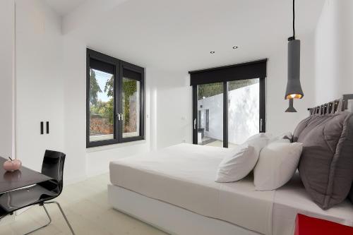 MichELe Luxury apartments by Smaris Collection في ماليا: غرفة نوم بيضاء بها سرير ومكتب ونوافذ