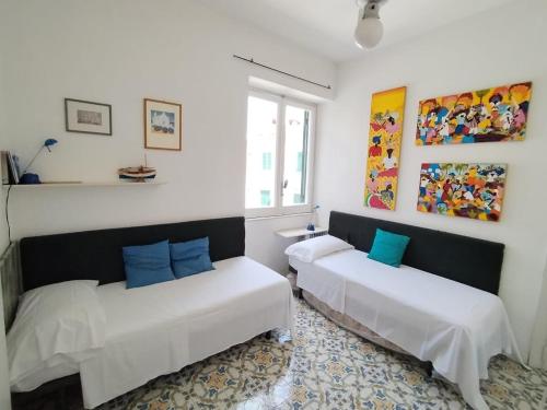 two beds in a room with white walls and blue pillows at Casa Franco in Ischia Town