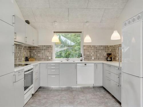 a white kitchen with white cabinets and a window at Holiday Home Talida - all inclusive - 12km from the sea by Interhome in Oksbøl